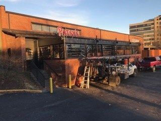 Storefront with red sign, outdoor display shelves, and parked cars in a parking lot at sunset