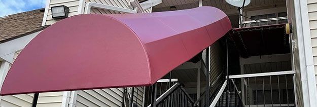 Pink awning over a building entrance with metal scaffolding underneath