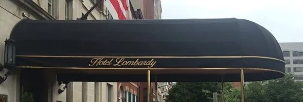 Black awning with gold trim and script above a storefront entrance in a city street