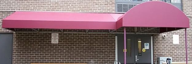 Pink awnings over a brick building entrance with a glass door and windows