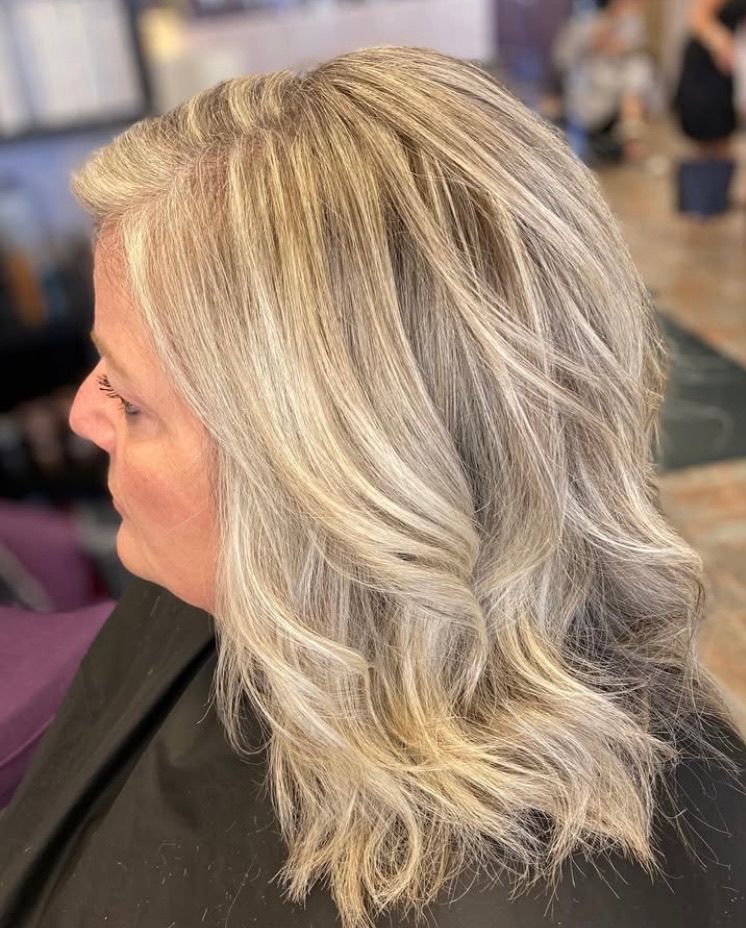 A woman with gray hair is sitting in a chair in a salon.