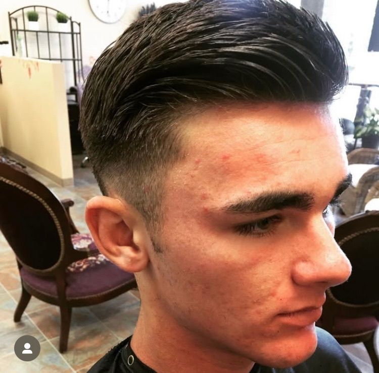 A young man is getting his hair cut in a salon