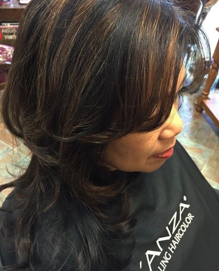 A woman with long hair is wearing a black anza hair color cape.