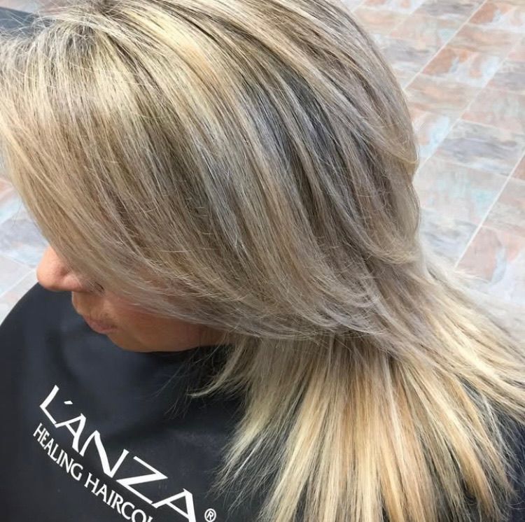 A woman with blonde hair is wearing a lanza healing hair color cape