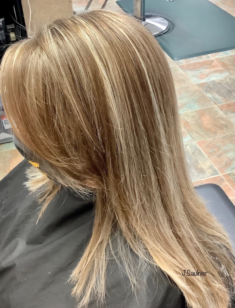 A woman with long blonde hair is sitting in a chair in a salon.