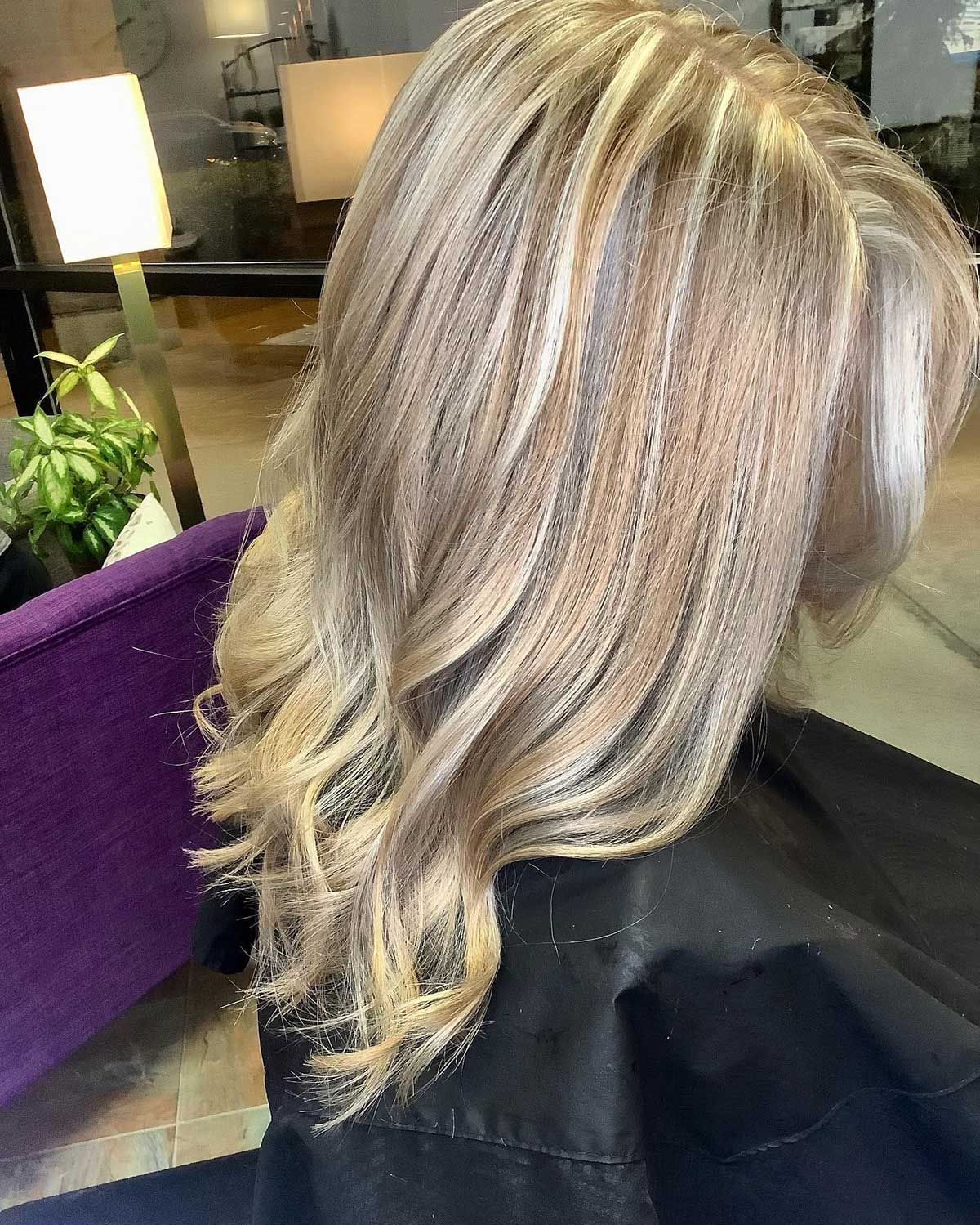 A woman with blonde hair is sitting in a chair in a salon.