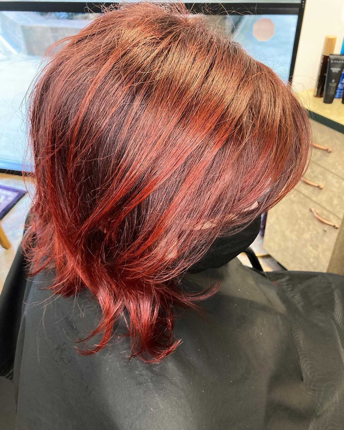 A woman with red hair is sitting in a chair in a salon.