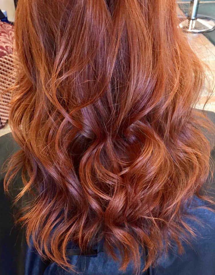 A woman with long red hair is sitting in a chair.