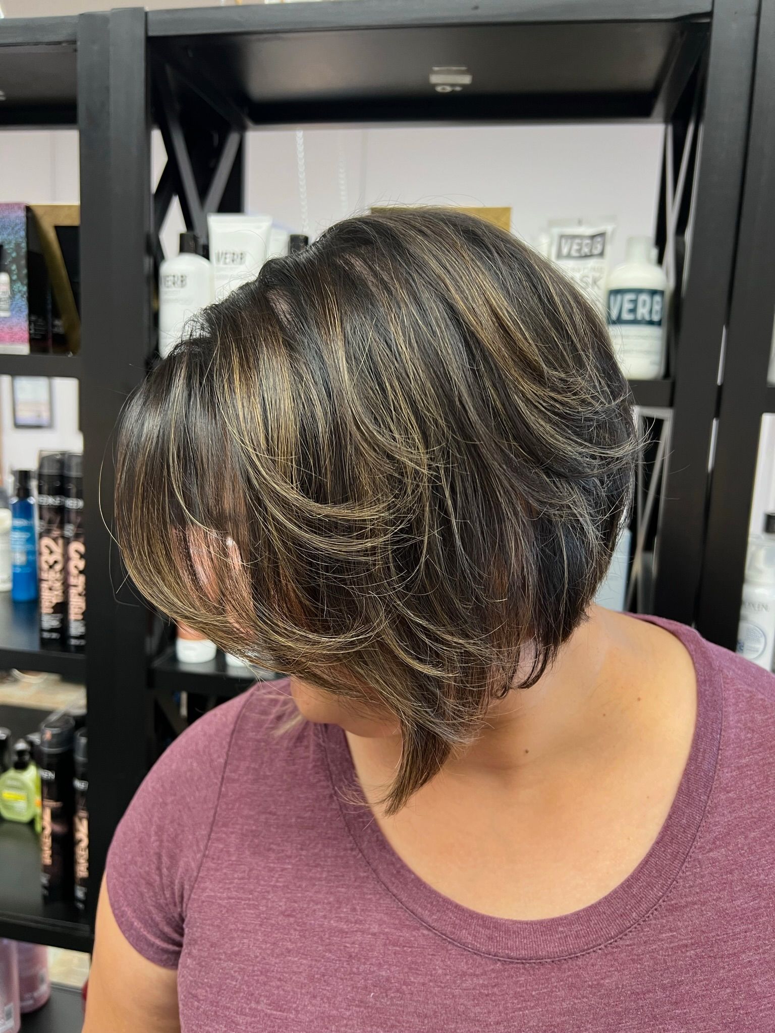A woman with short hair is standing in front of a shelf.
