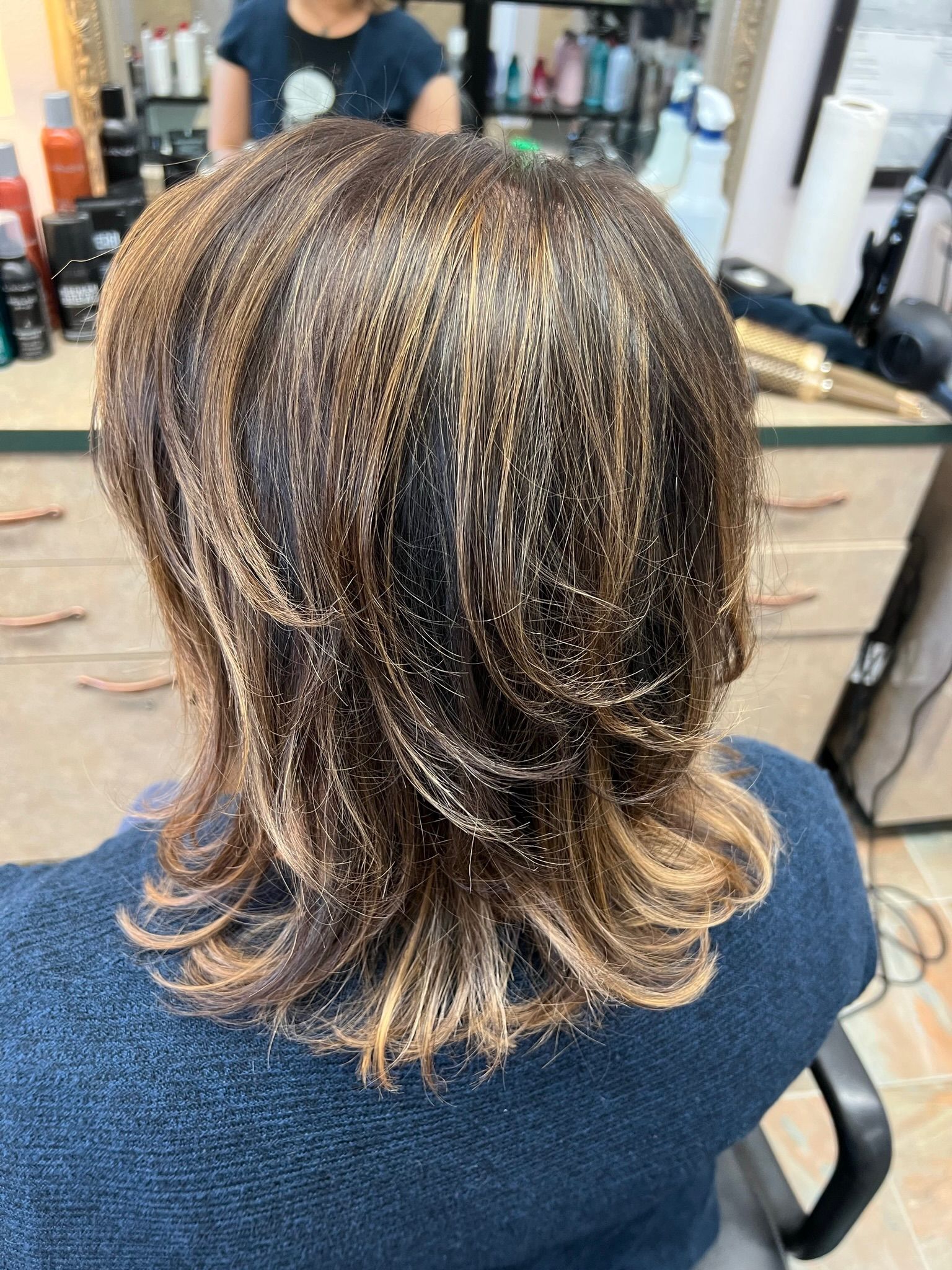 A woman is sitting in a chair with her hair in a salon.