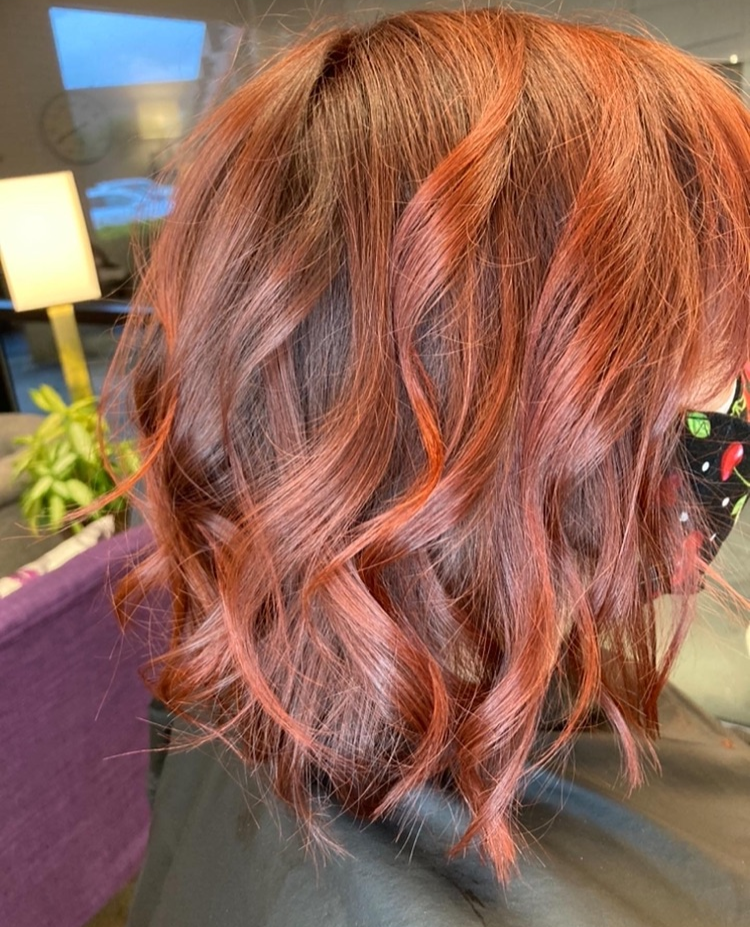 A woman with red hair is wearing a mask.