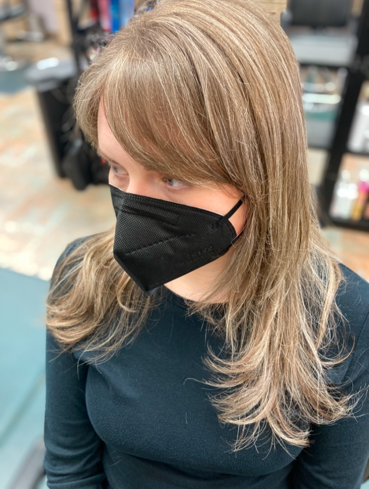 A woman wearing a black face mask is sitting in a chair.