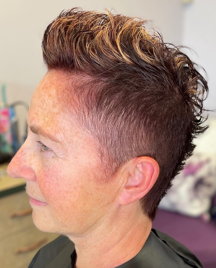 A woman with short hair is wearing a black cape