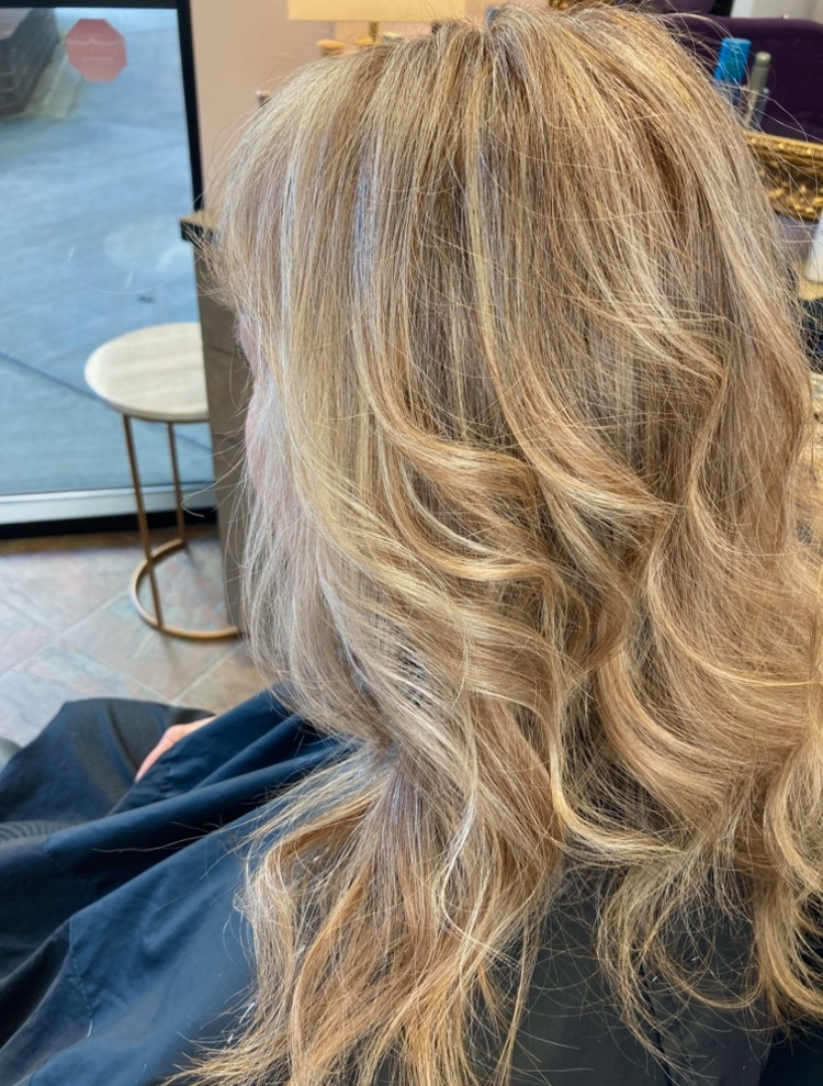 A woman with blonde hair is sitting in a chair in a salon.
