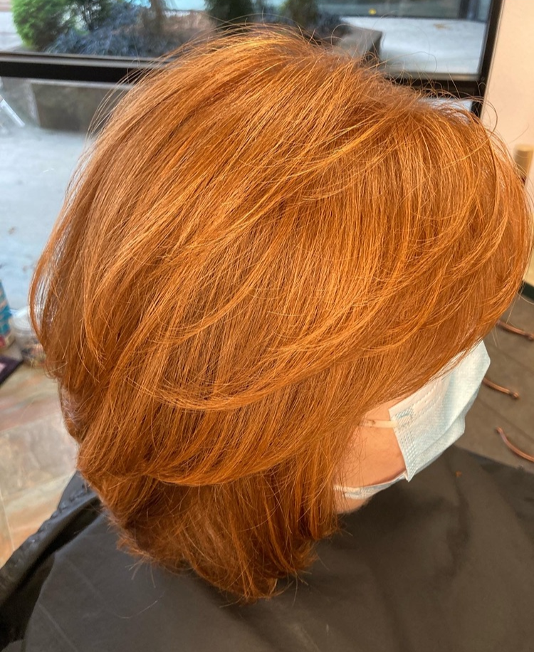 A woman with red hair is wearing a face mask.