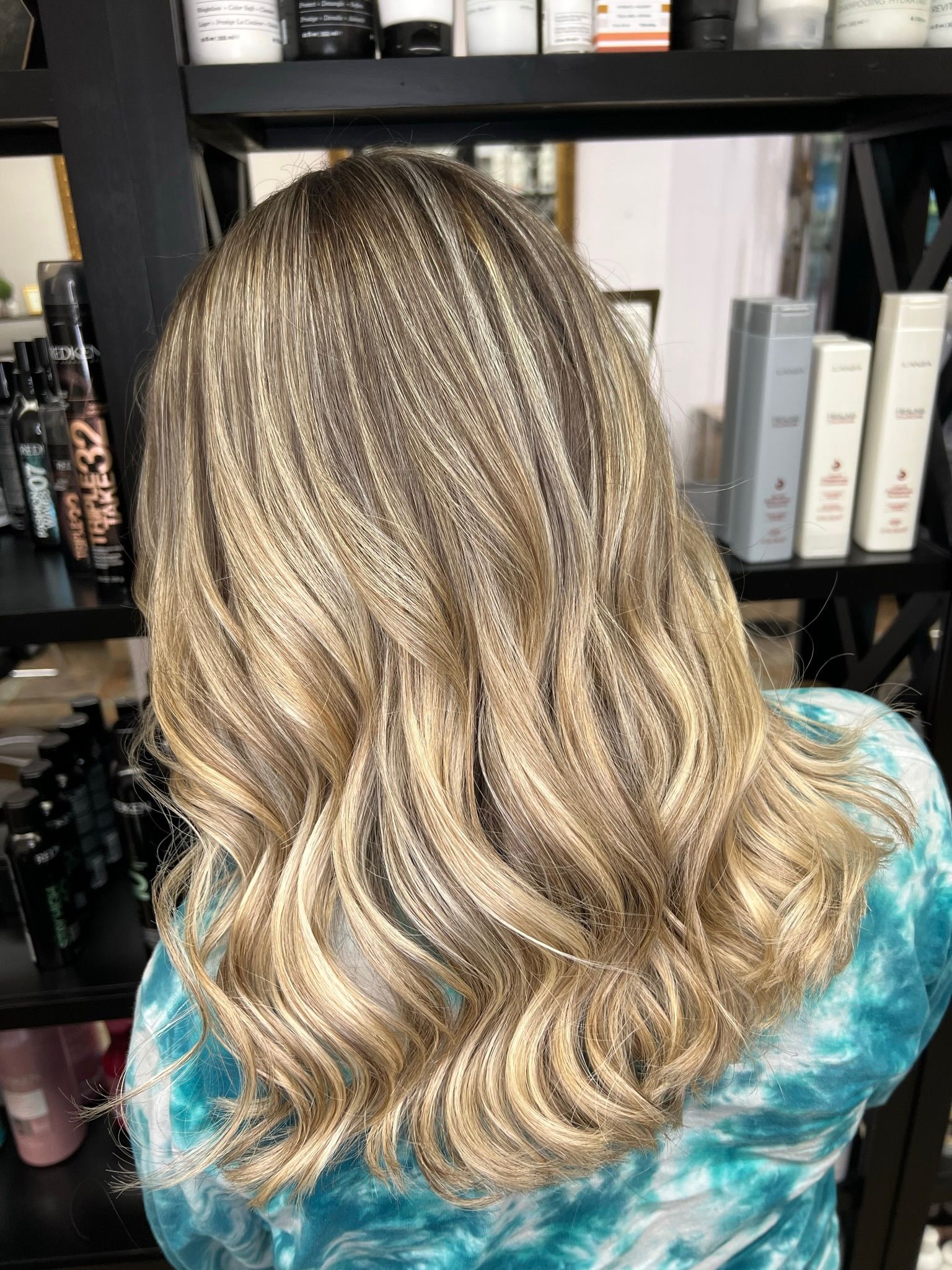 A woman with blonde hair is standing in front of a shelf of hair products.