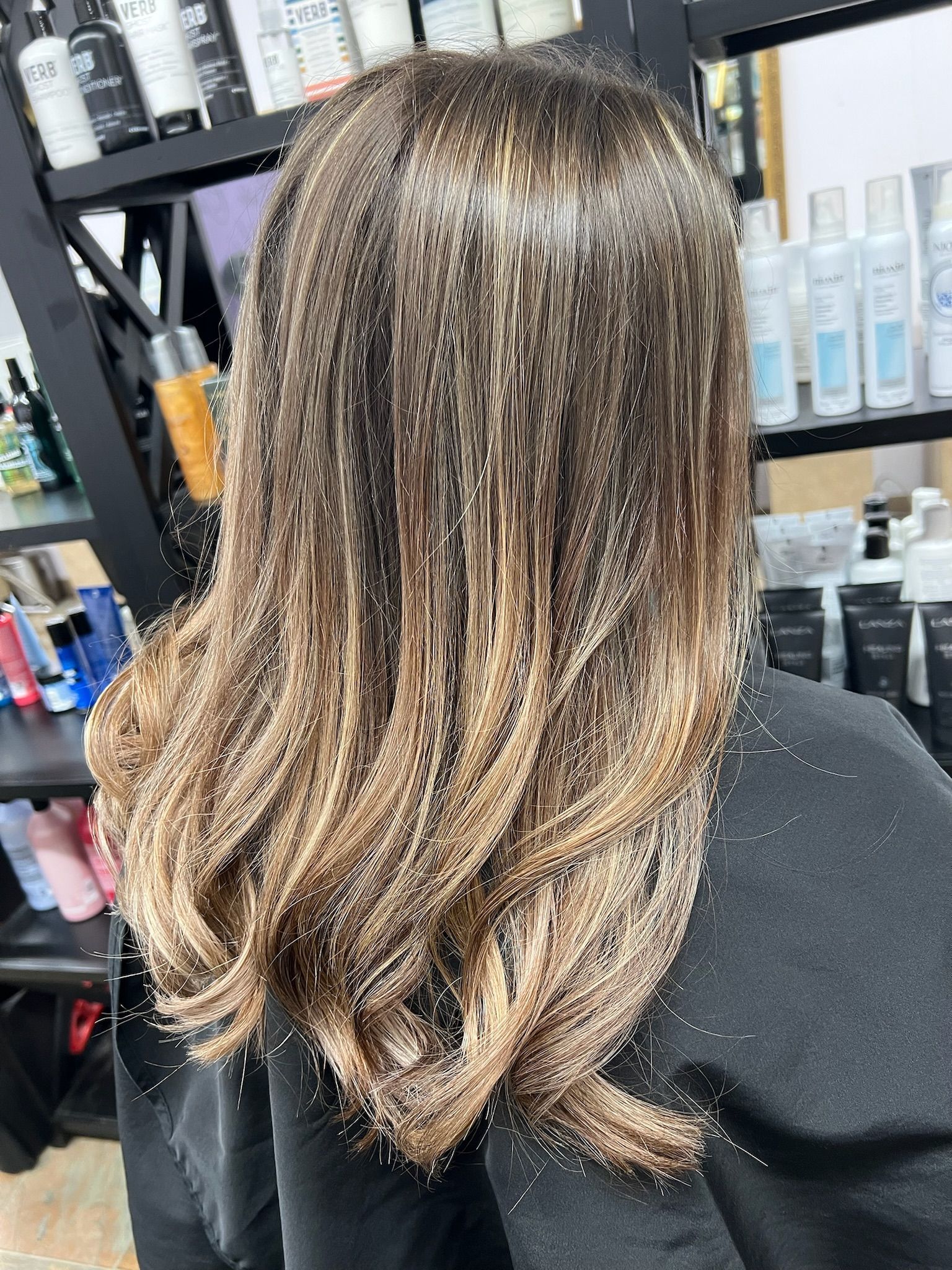 A woman with long hair is sitting in a chair in a salon.