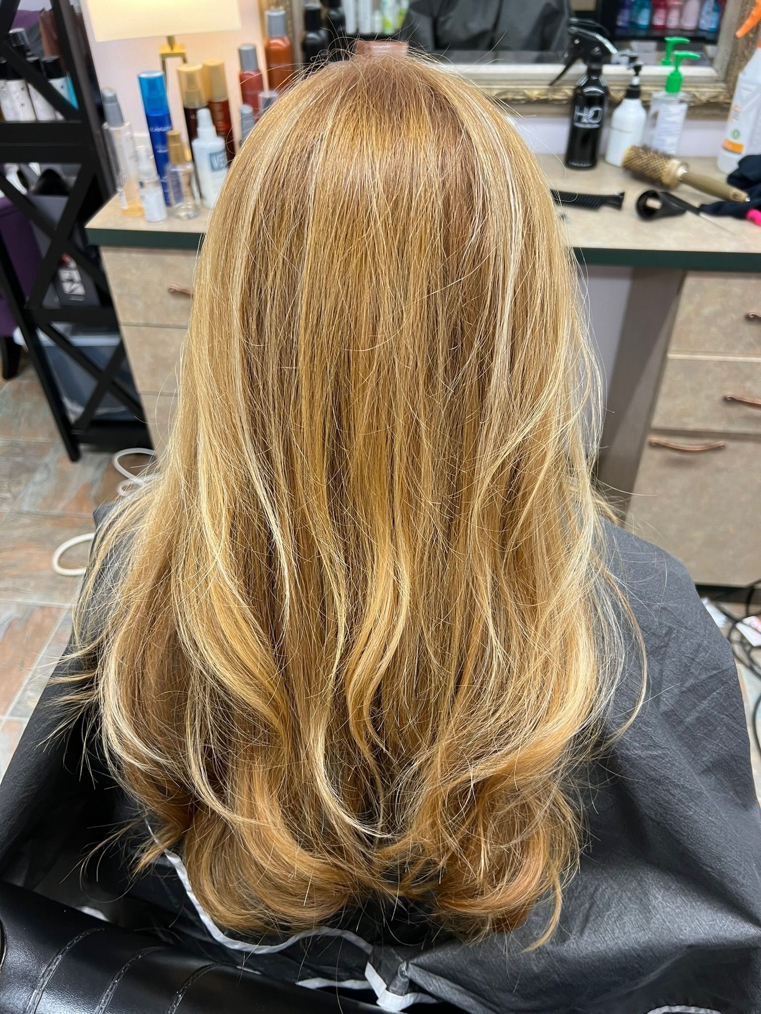 A woman with long blonde hair is sitting in a chair at a hair salon.