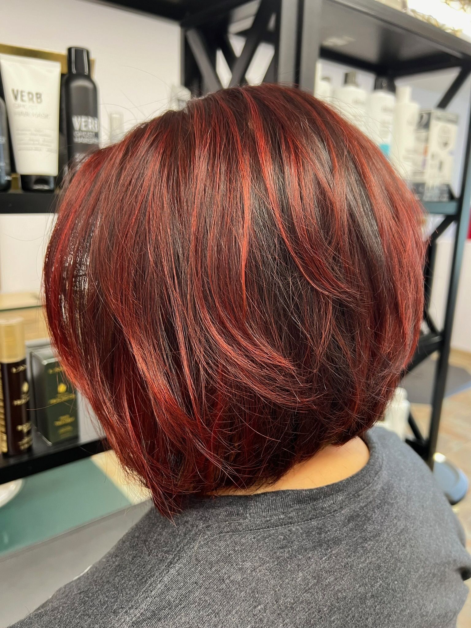 A woman with red hair is sitting in a chair in a salon.