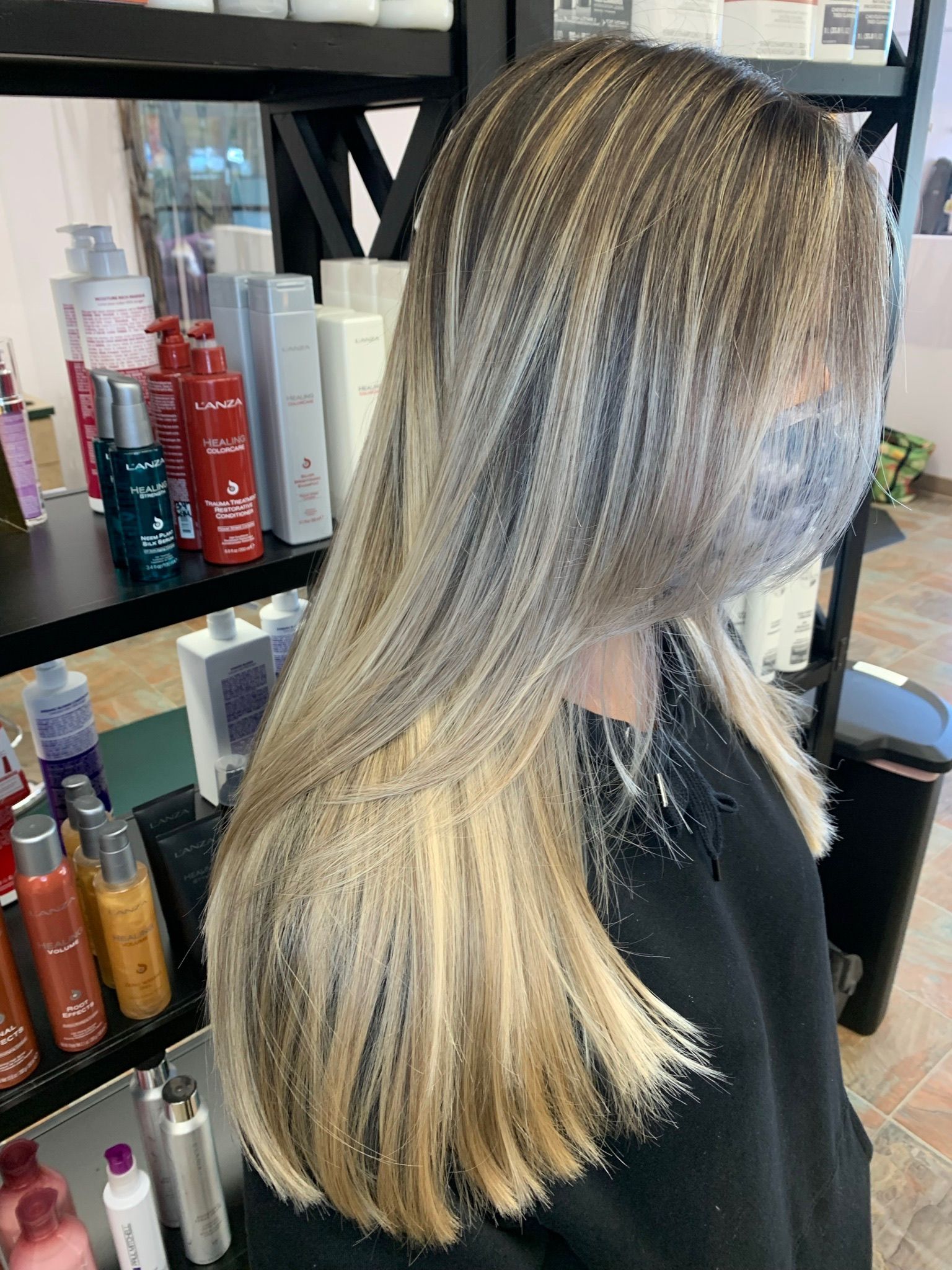 A woman with long blonde hair is sitting in a chair in a salon.