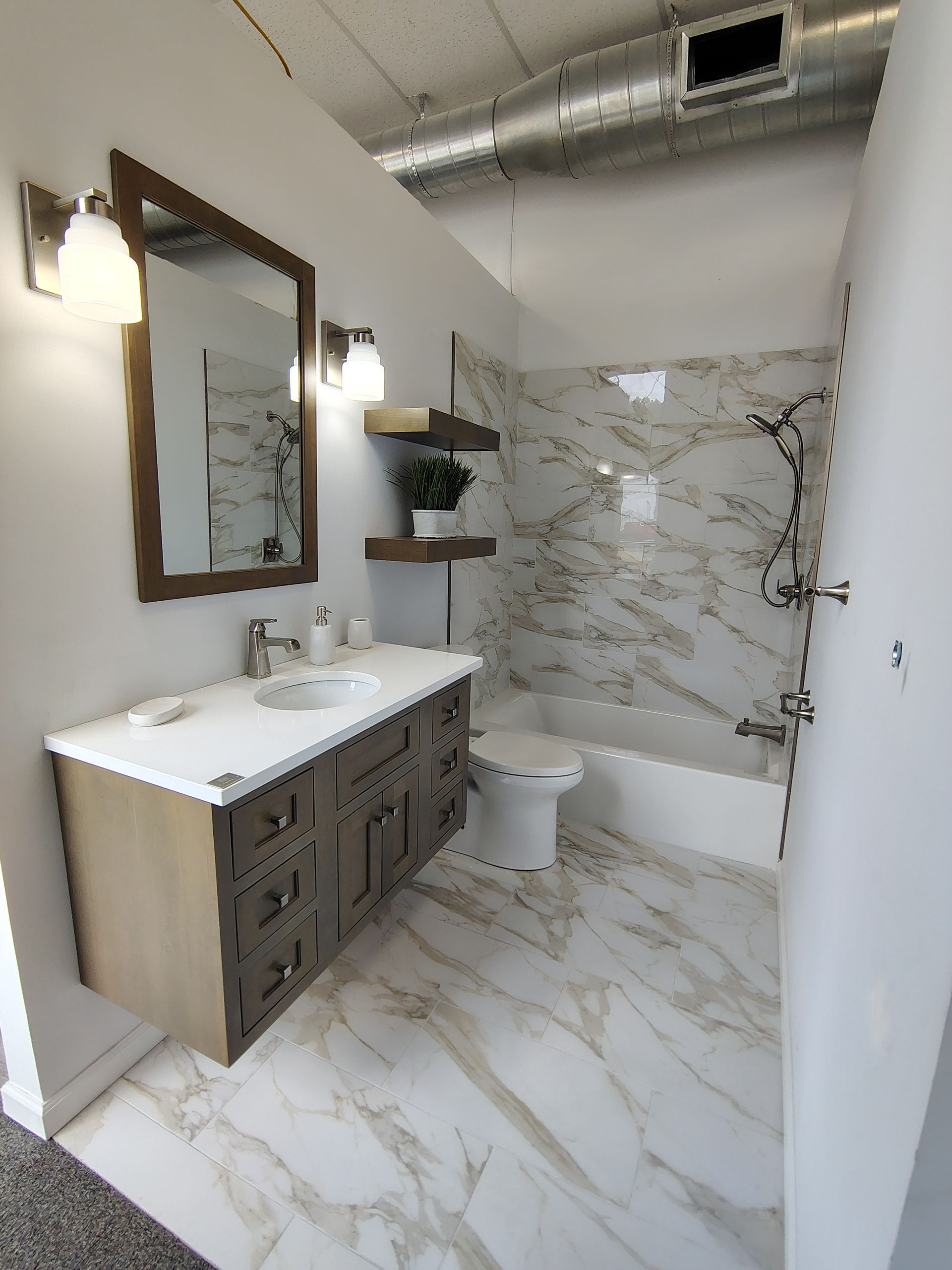 A bathroom with a sink, toilet, shower, and mirror