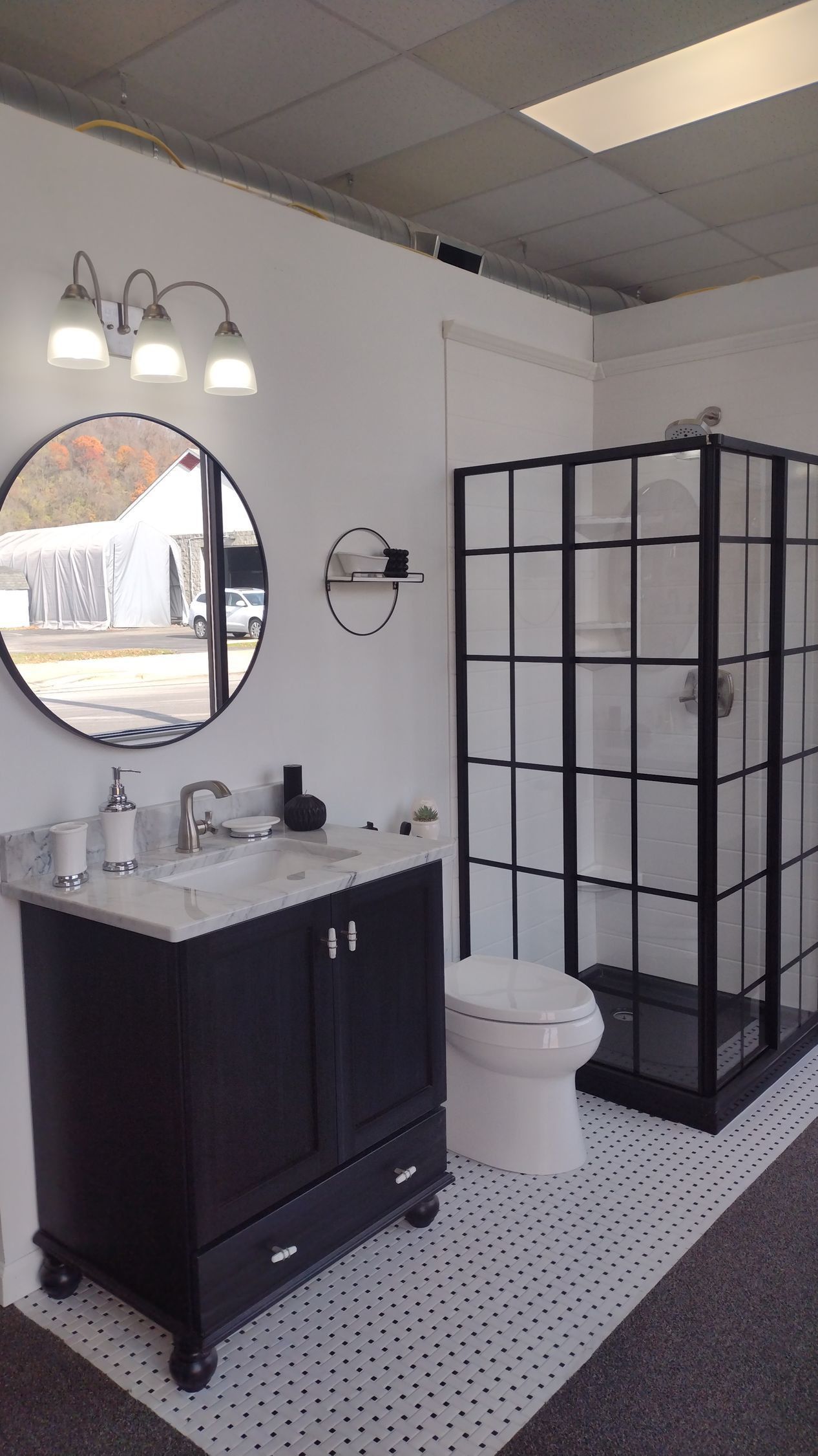 A bathroom with a sink, toilet, shower, and mirror