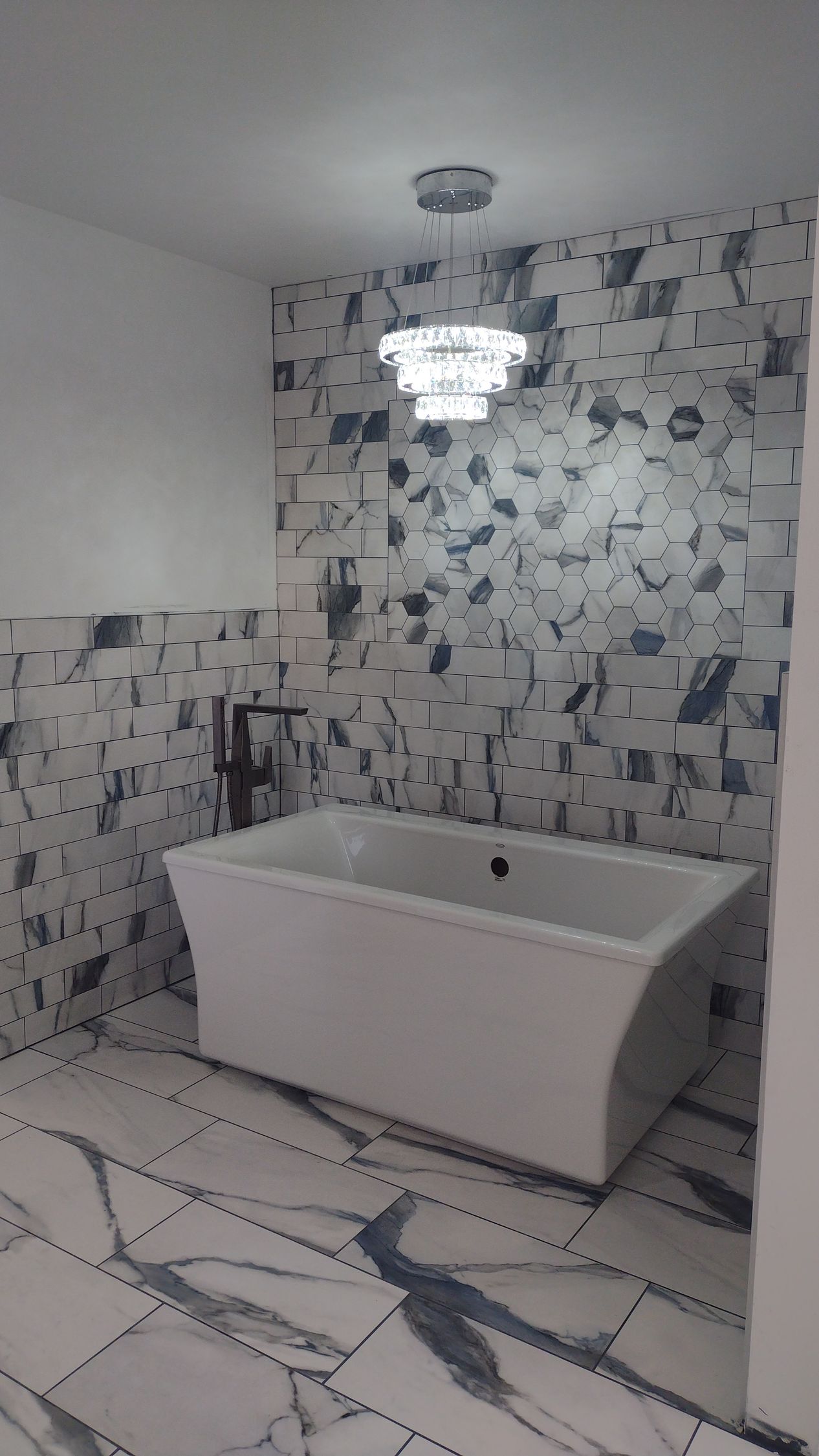 A bathroom with a bathtub and a chandelier hanging from the ceiling