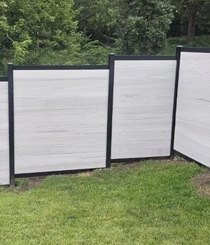 A white wooden fence with black trim is sitting on top of a lush green lawn.