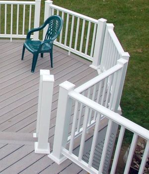 A green chair sits on a deck next to a white railing