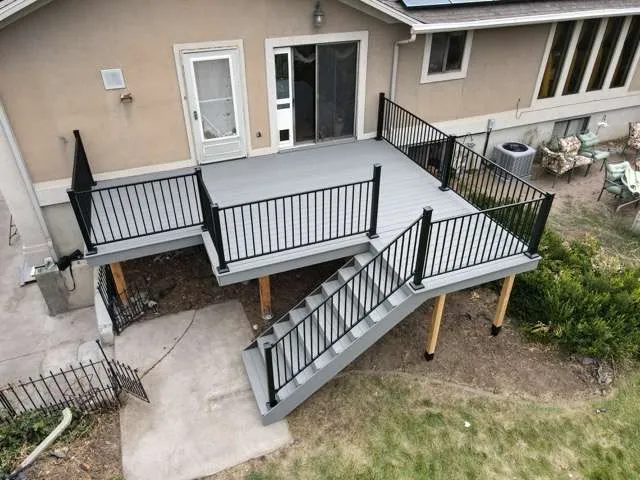 An aerial view of a deck with stairs and a railing in front of a house.