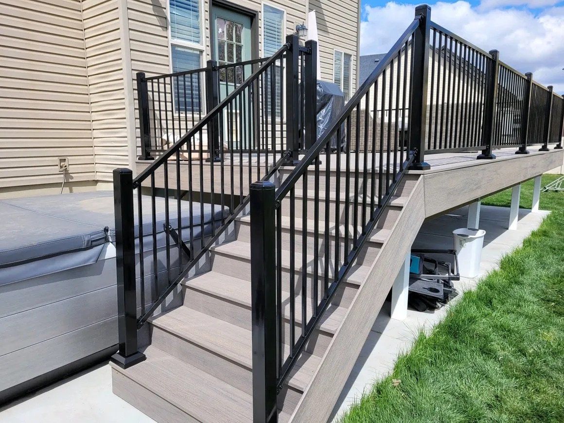 A deck with stairs leading up to it and a black railing.