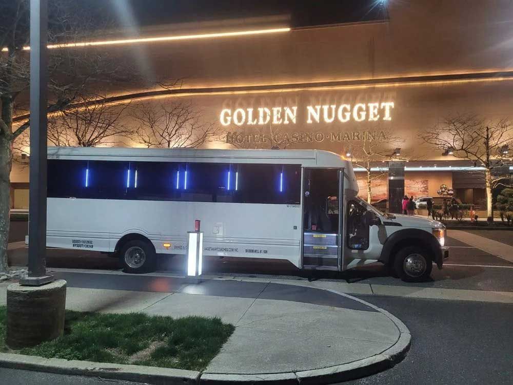 White bus parked outside the Golden Nugget casino at night; illuminated sign.