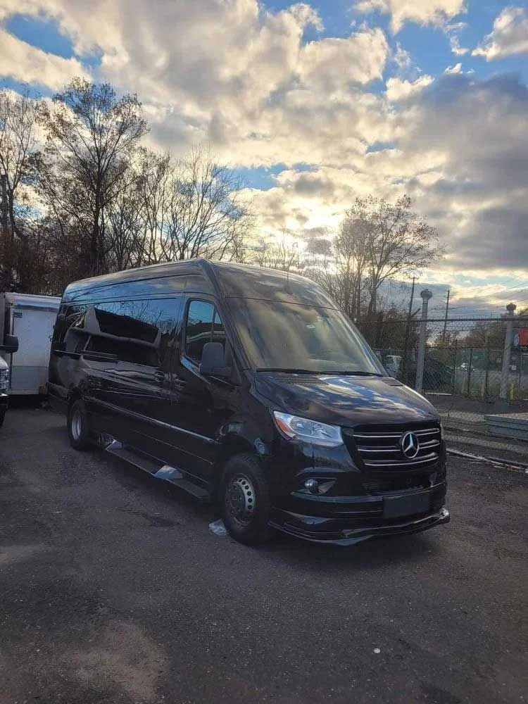 Black Mercedes-Benz Sprinter van parked outdoors on a cloudy day.