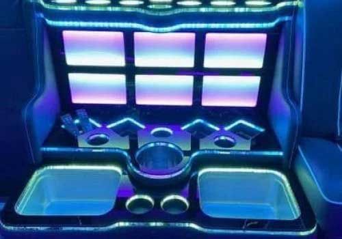 Interior of a limo with blue and purple LED lighting; includes drink holders and square lighted panels.