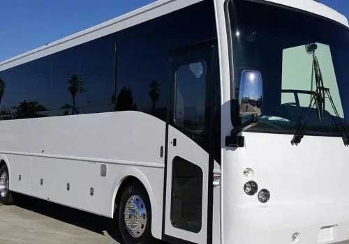 White charter bus with tinted windows parked outside.