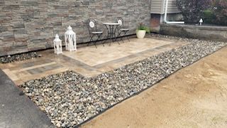 A patio with a table and chairs in front of a stone wall.