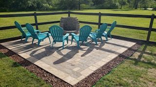 A group of blue chairs are sitting on a patio next to a fire pit.