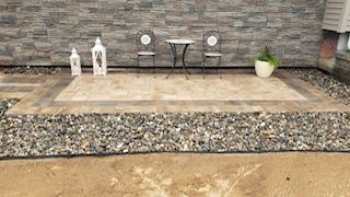 A patio with a table and chairs in front of a brick wall.