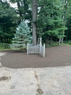 A driveway with a gate and trees in the background.