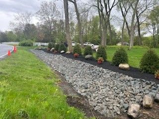A row of rocks and mulch along the side of a road.
