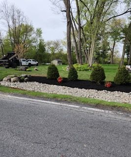 There is a truck parked on the side of the road next to a lush green field.