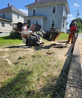 A man is standing next to a bulldozer in front of a house.