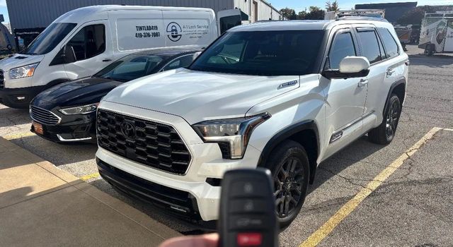 Silver SUV parked in a lot, with a key fob in the foreground and vans behind it