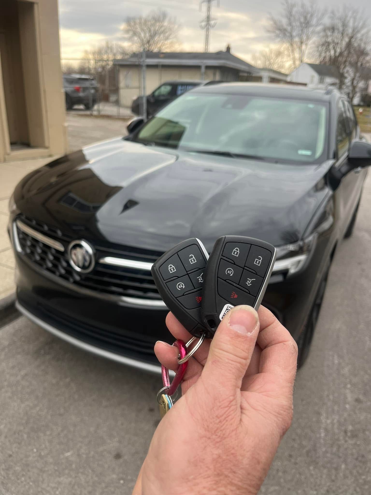 Hand holding car keys in front of a black Volkswagen SUV in a driveway