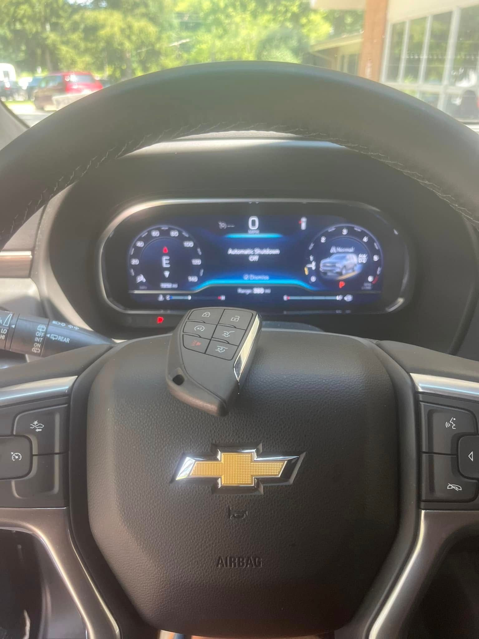 Chevrolet steering wheel and digital dashboard view from the driver’s seat inside a parked car.