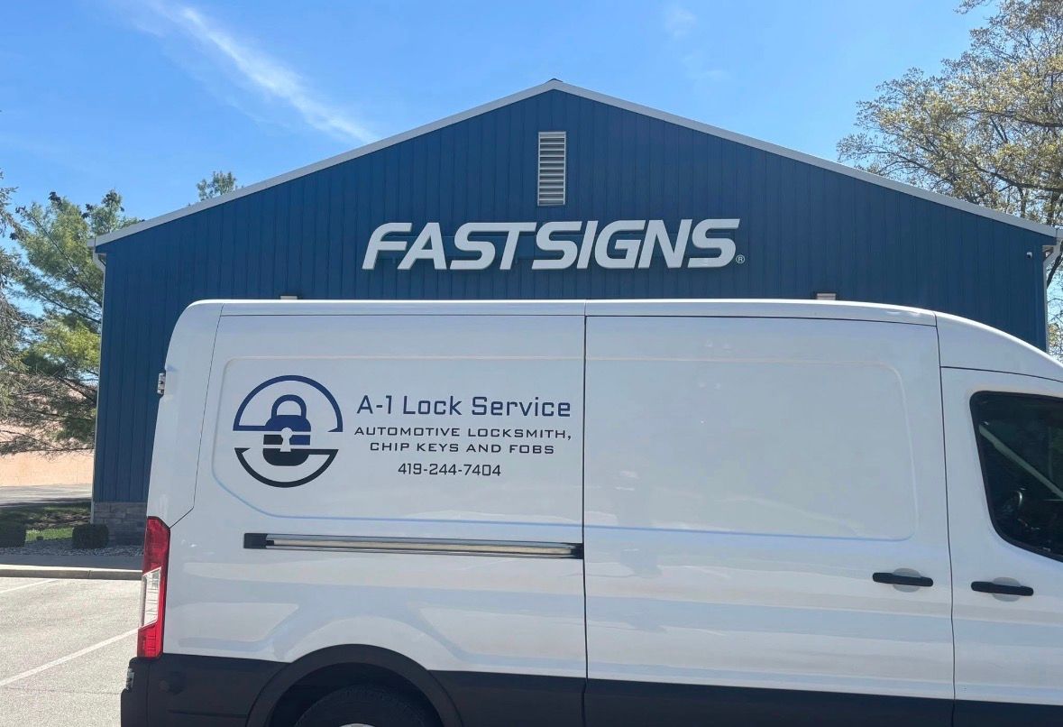 White work van parked in front of a blue FASTSIGNS building under a clear sky