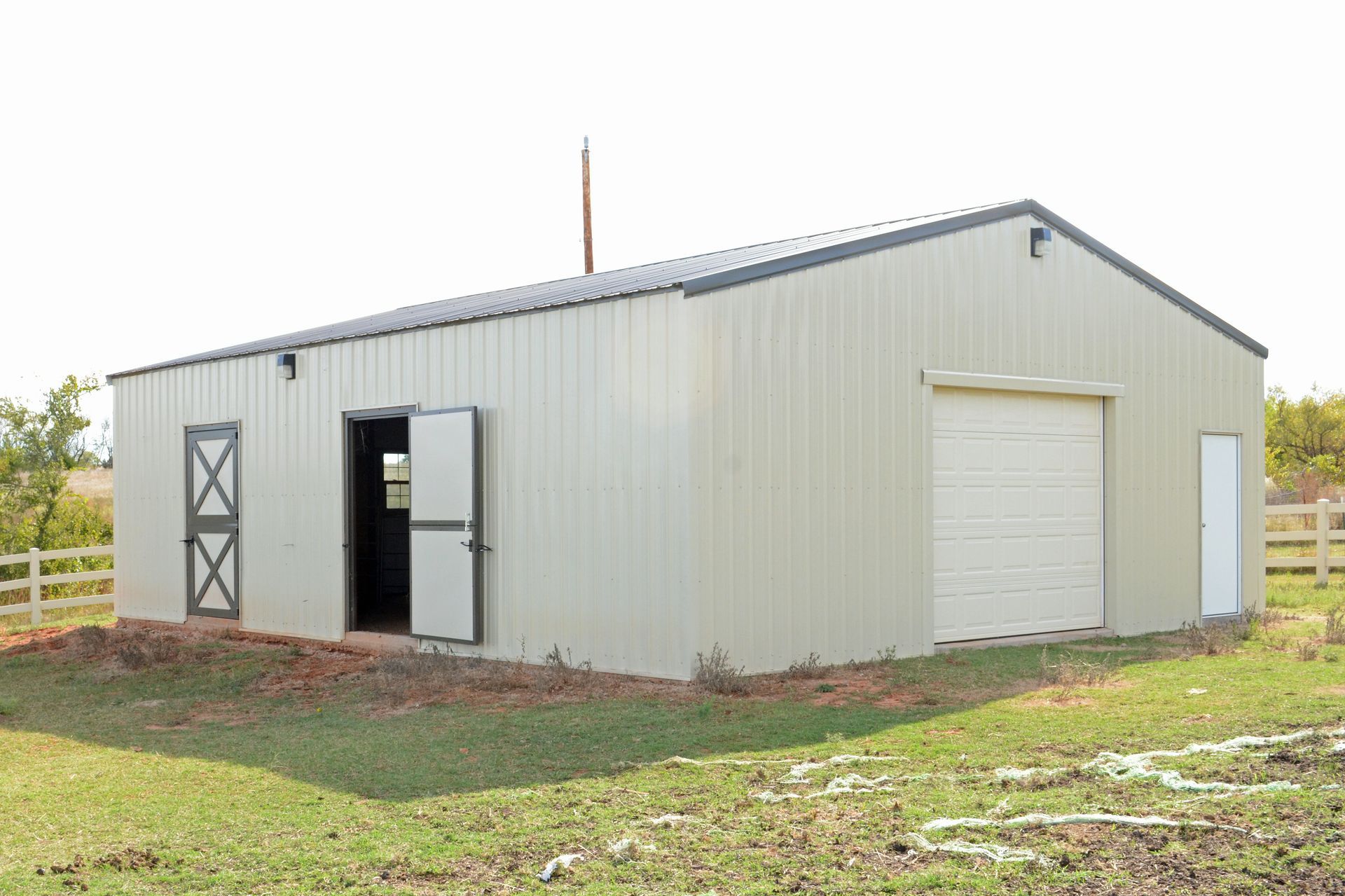 Metal building with tan walls, black roof, garage door, and two doors.