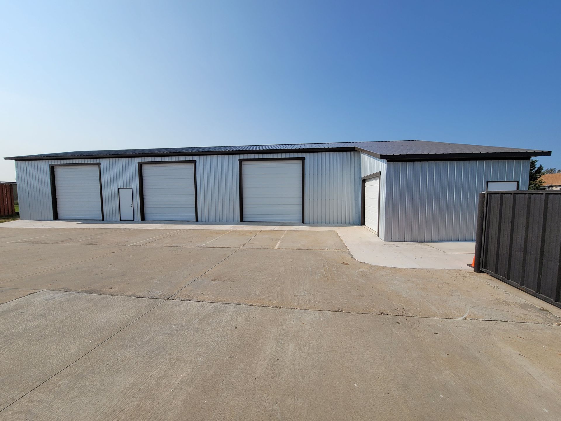 Metal storage units with white garage doors, on a concrete lot.