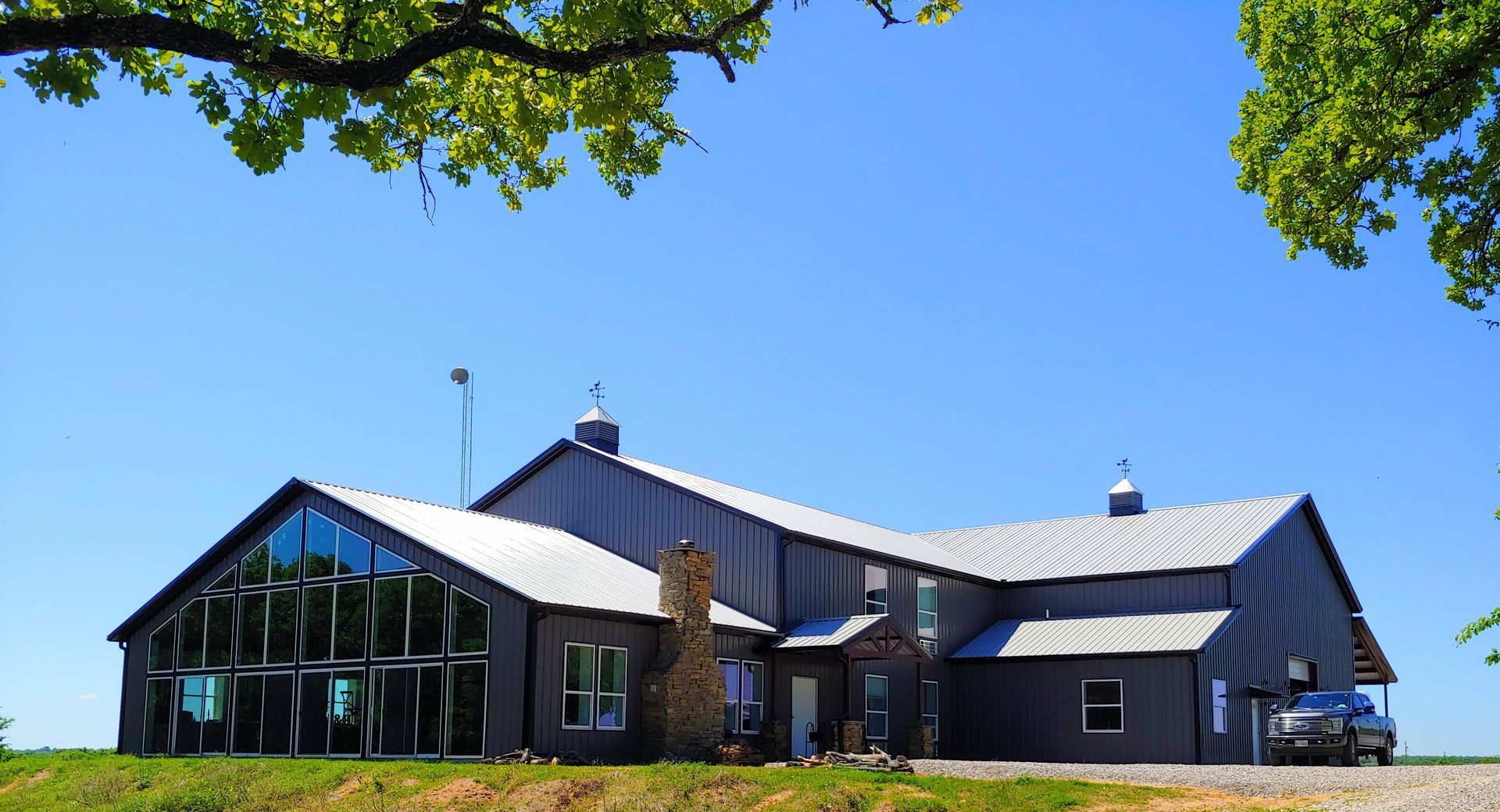 Dark gray modern barn with a glass facade, on a sunny day.