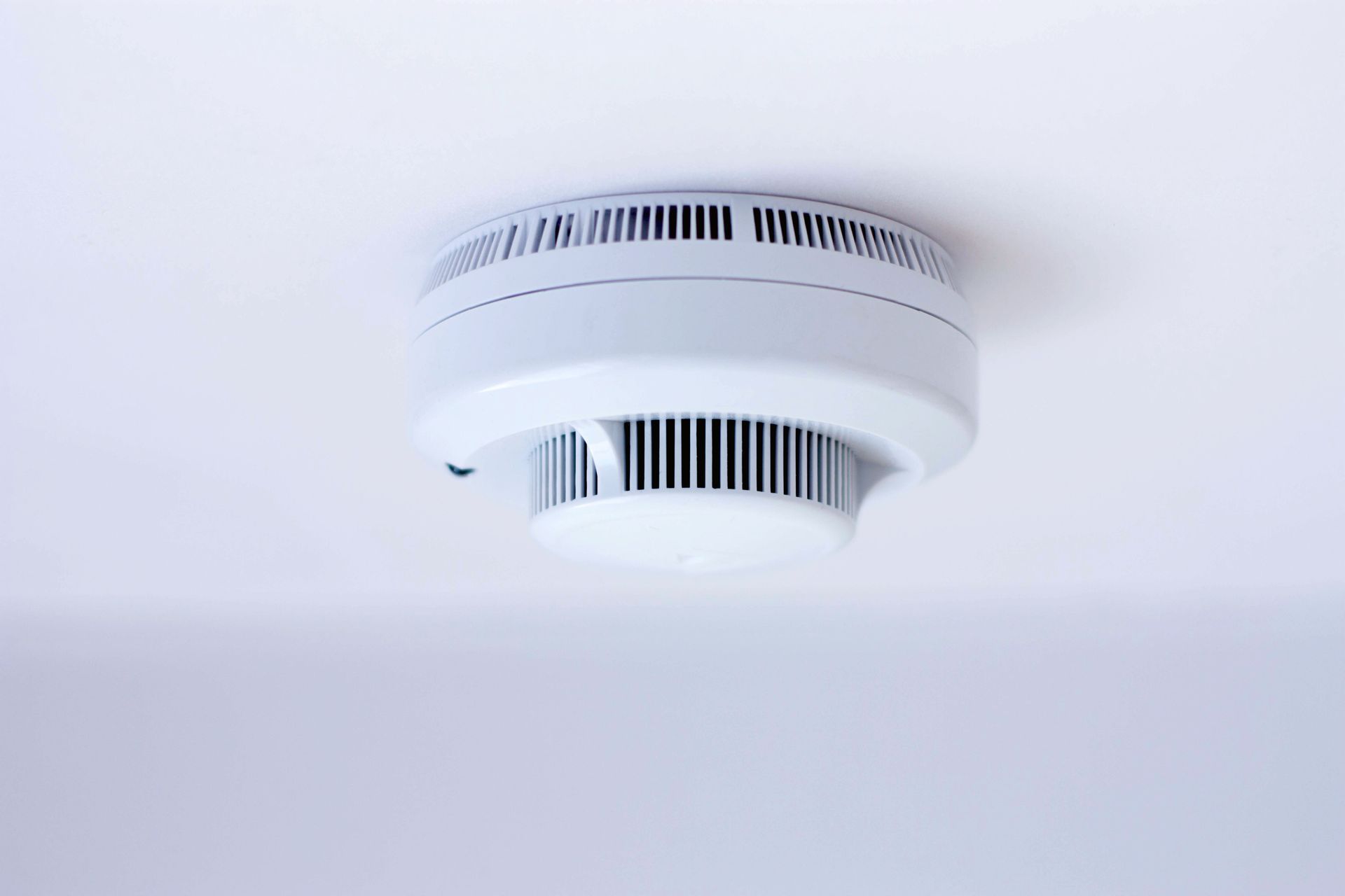 White smoke detector mounted on a white ceiling.